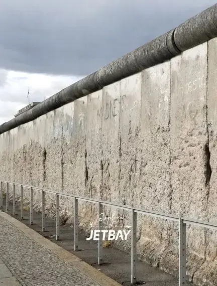Historic Berlin Wall remnant with barbed wire and protective railing showcasing Cold War heritage