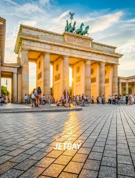 Brandenburg Gate's neoclassical columns illuminated by golden sunset light with tourists gathering in Berlin
