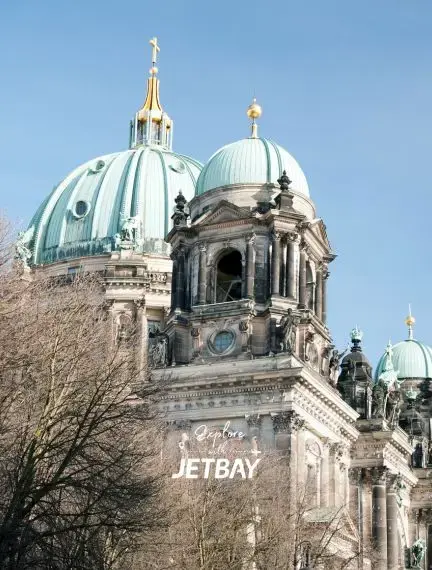 Berlin Cathedral's baroque architecture with distinctive green copper domes against clear blue sky