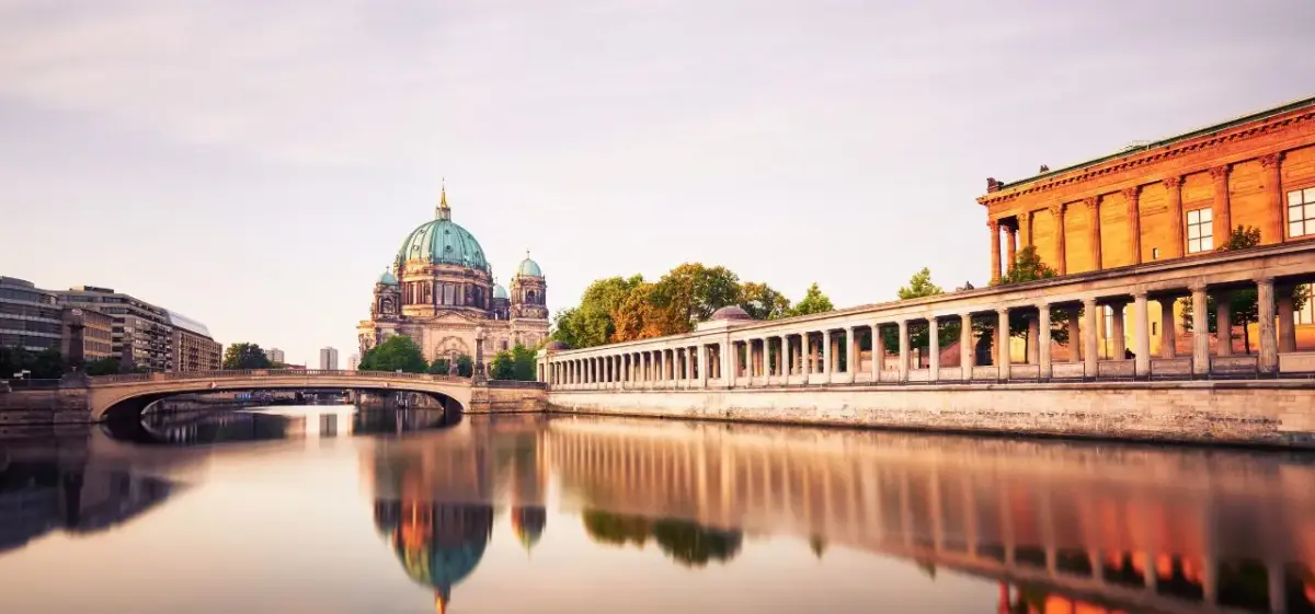 Berlin Cathedral and Museum Island reflecting in Spree River at golden hour, showcasing Germany's capital
