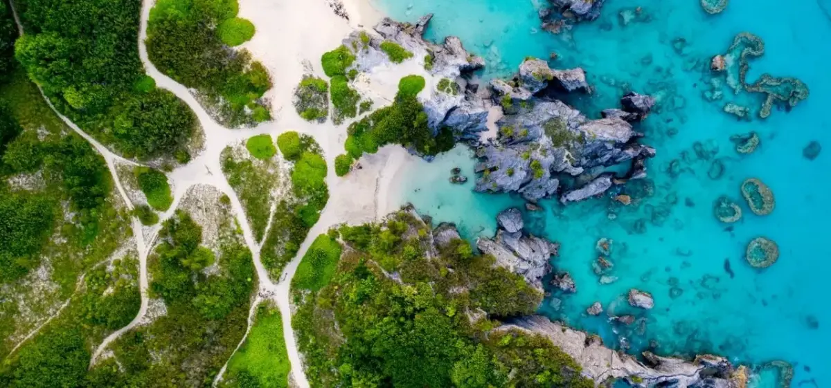 Aerial view of pristine Bermuda coastline with turquoise waters, coral formations, and lush tropical vegetation
