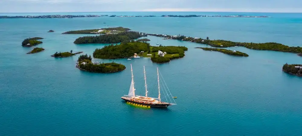 Luxury sailing yacht anchored in turquoise waters near Bermuda's lush private islands and coral reefs
