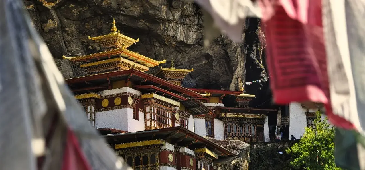 Traditional Bhutanese monastery with golden roofs nestled against dramatic mountain cliffs in the Himalayas