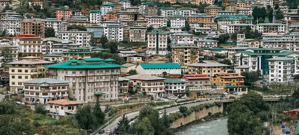 Colorful multi-story buildings cascade down hillsides in Thimphu, Bhutan's capital city and luxury travel destination