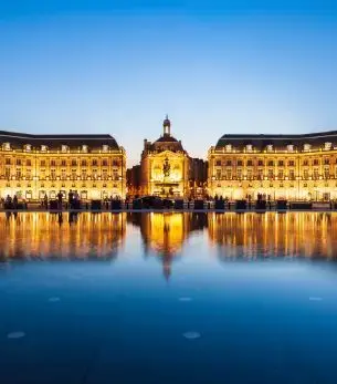 Place de la Bourse illuminated at dusk with golden reflections in Bordeaux's Miroir d'eau fountain