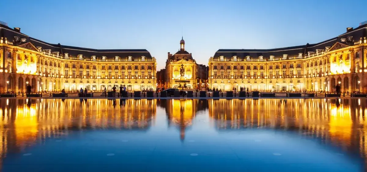 Place de la Bourse in Bordeaux illuminated at twilight with golden reflections in the water mirror