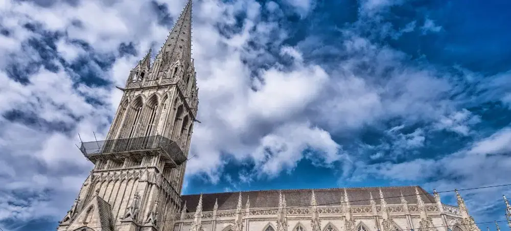 Gothic spire of Saint-André Cathedral reaching toward dramatic blue sky in historic Bordeaux, France