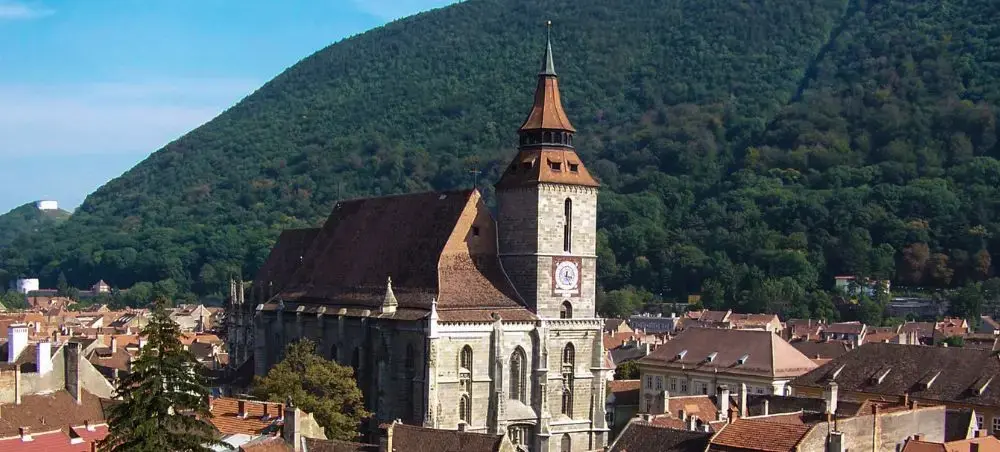 Historic Black Church dominates Brasov's medieval cityscape with forested Carpathian Mountains rising behind