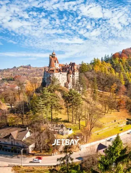 Bran Castle perched on forested hillside in autumn colors near Brasov, Romania for luxury travel