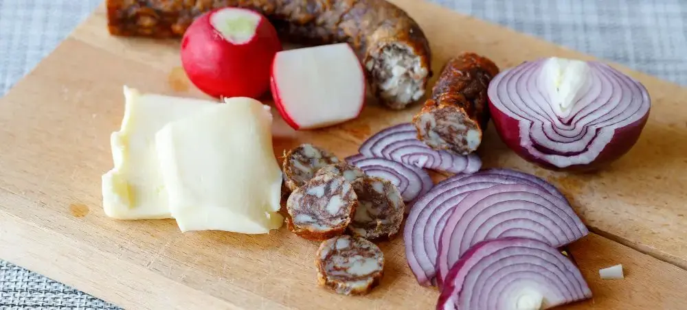 Artisanal Romanian charcuterie board featuring local sausages, aged cheese, and fresh vegetables from Brasov region