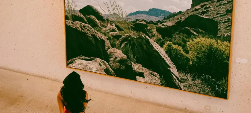 Traveler admiring large landscape artwork featuring Australian mountain scenery in Brisbane gallery