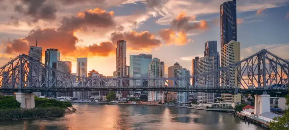 Brisbane skyline at sunset with Story Bridge spanning the Brisbane River and modern skyscrapers reflecting golden light