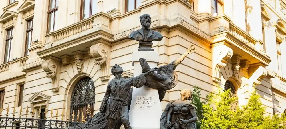 Historic bronze monument with classical figures adorning elegant Bucharest architecture during golden hour