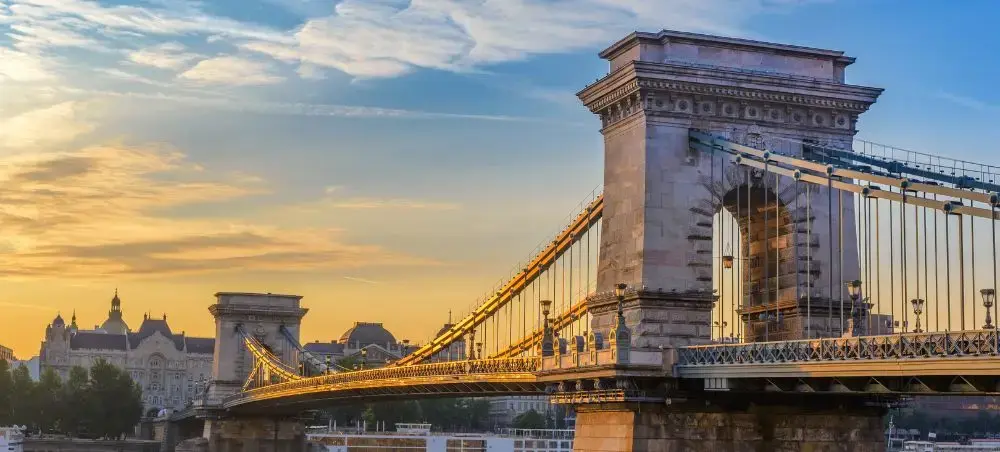 Historic Chain Bridge spanning the Danube River in Budapest at golden hour with illuminated architecture