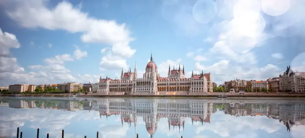 Hungarian Parliament Building reflecting in Danube River waters under dramatic cloudy sky in Budapest