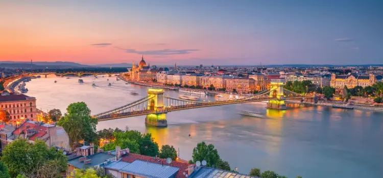 Budapest skyline at sunset featuring illuminated Chain Bridge over Danube River and Parliament building