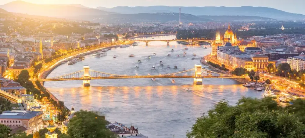 Budapest skyline at sunset showcasing illuminated Parliament building and Chain Bridge over Danube River