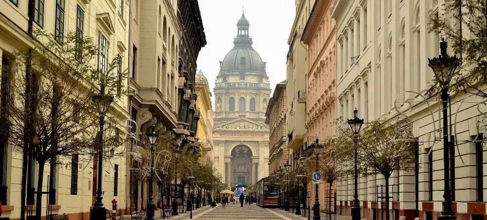 Historic Budapest street leading to St. Stephen's Basilica dome, showcasing elegant architecture and cobblestone charm