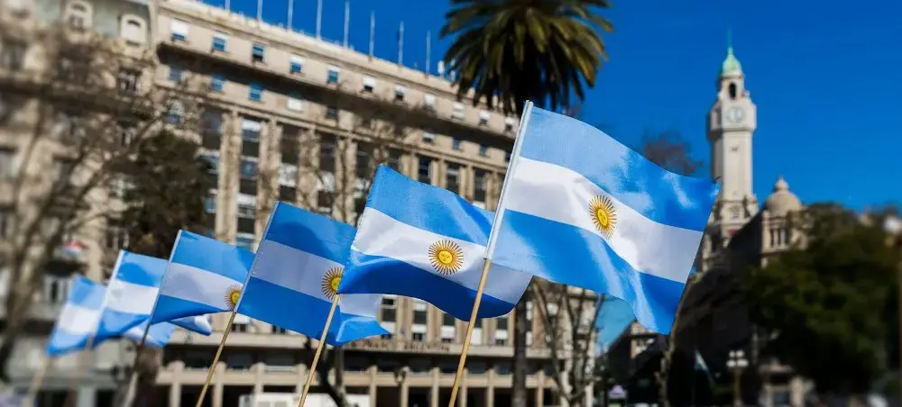 Argentine flags with golden sun emblems waving in Buenos Aires plaza for luxury travel destination