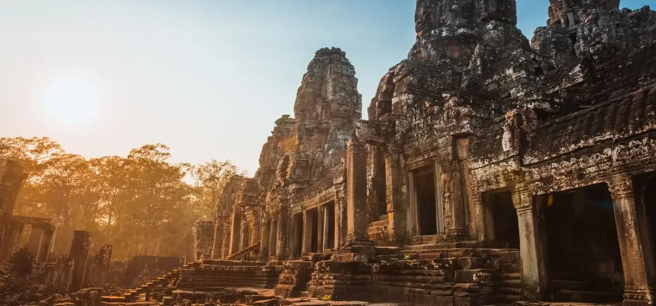 Ancient Angkor temple complex in Cambodia bathed in golden sunrise light, showcasing intricate Khmer architecture and stone carvings