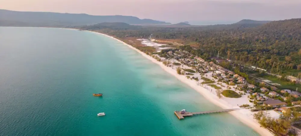 Aerial view of pristine Cambodian coastline with turquoise waters, white sand beach, and luxury resorts