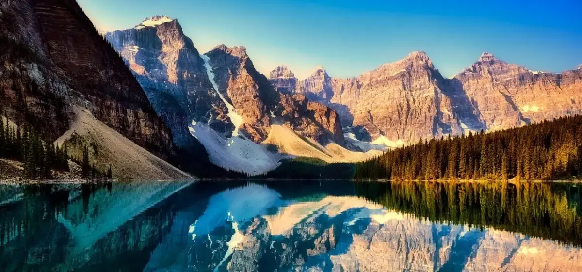 Majestic Canadian Rockies reflected in pristine turquoise lake waters at golden hour sunrise