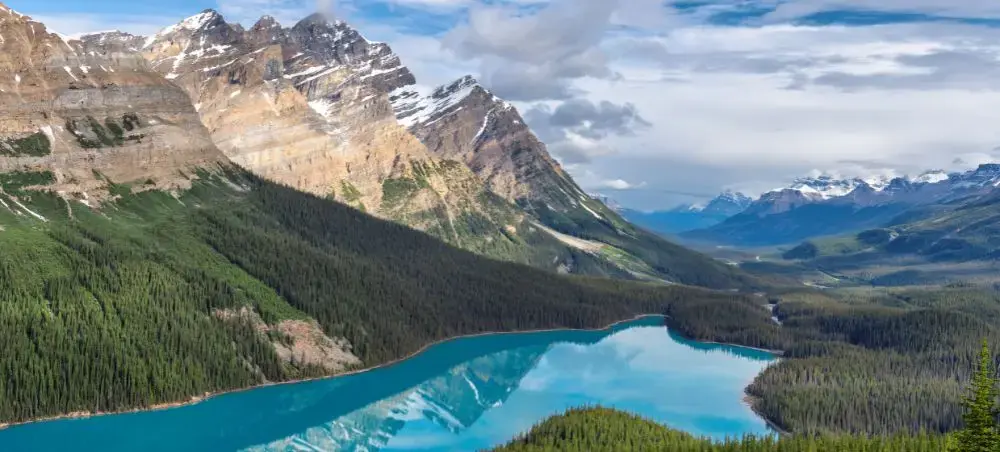 Pristine turquoise lake surrounded by snow-capped Canadian Rockies and dense evergreen forests