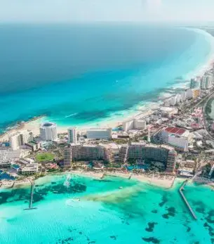Aerial view of Cancun's pristine turquoise waters and white sand beaches with luxury resorts along the coast