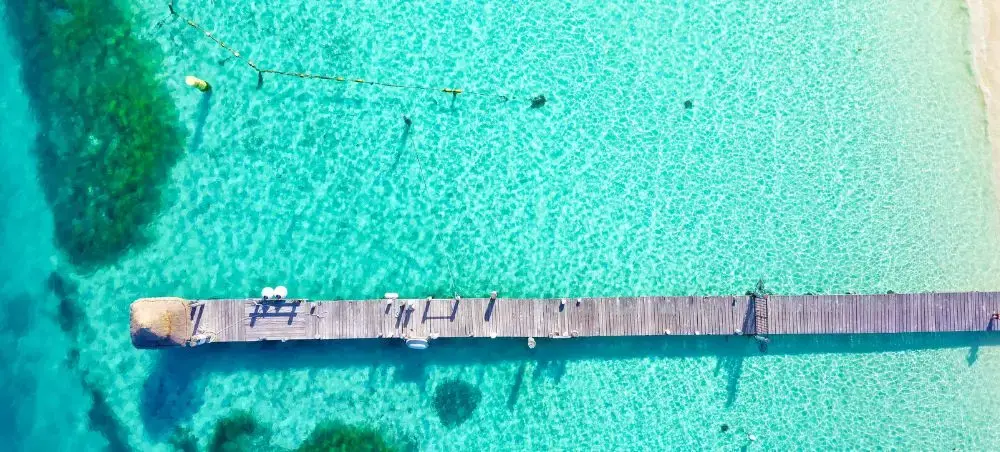 Aerial view of wooden pier extending over crystal-clear turquoise waters in Cancun's Caribbean coast