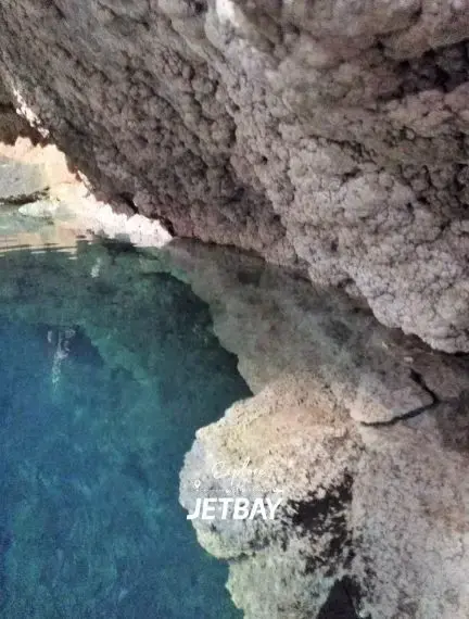 Crystal-clear cenote waters surrounded by ancient limestone formations in Cancun's underground cave system