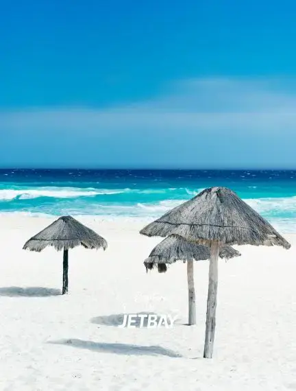 Pristine white sand beach with traditional palapa umbrellas overlooking turquoise Caribbean waters in Cancun
