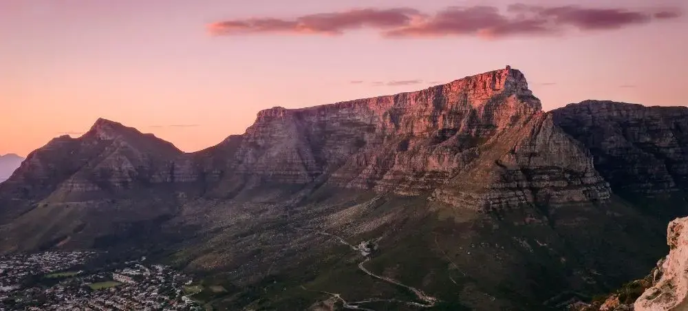 Table Mountain's dramatic cliffs illuminated by golden sunset light overlooking Cape Town cityscape below