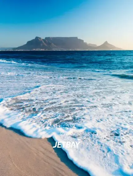 Table Mountain rises majestically above Cape Town's pristine coastline with turquoise waves washing sandy shores