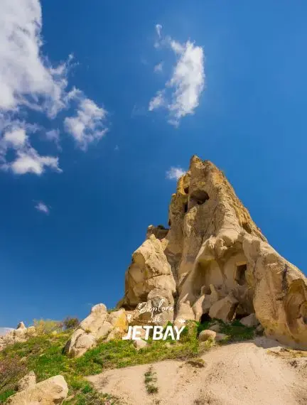 Ancient cave dwellings carved into towering rock formations under brilliant blue skies in Cappadocia