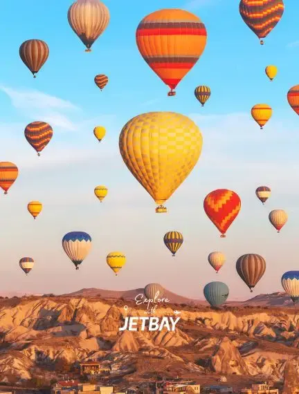 Colorful hot air balloons floating above Cappadocia's unique rock formations during golden hour sunrise