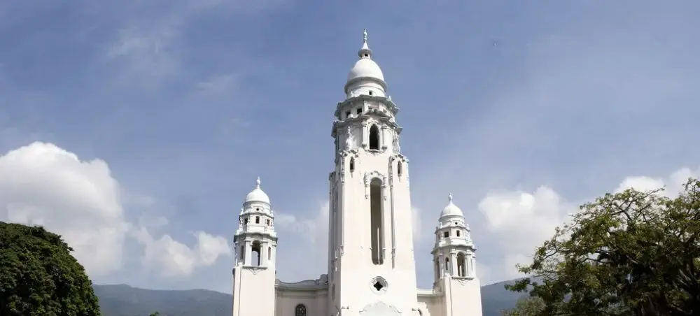 Historic white cathedral with twin bell towers and central dome in Caracas, Venezuela under blue sky