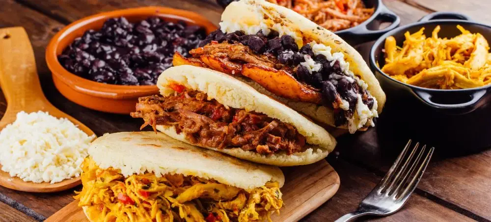 Traditional Venezuelan arepas filled with black beans and meat served with sides in Caracas dining setting