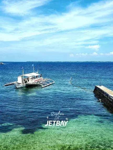 Crystal clear turquoise waters surround traditional Filipino outrigger boat near Cebu's pristine coastline