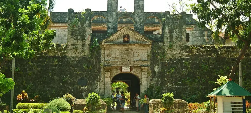 Historic Fort San Pedro entrance gate with stone walls and tropical gardens in Cebu City, Philippines