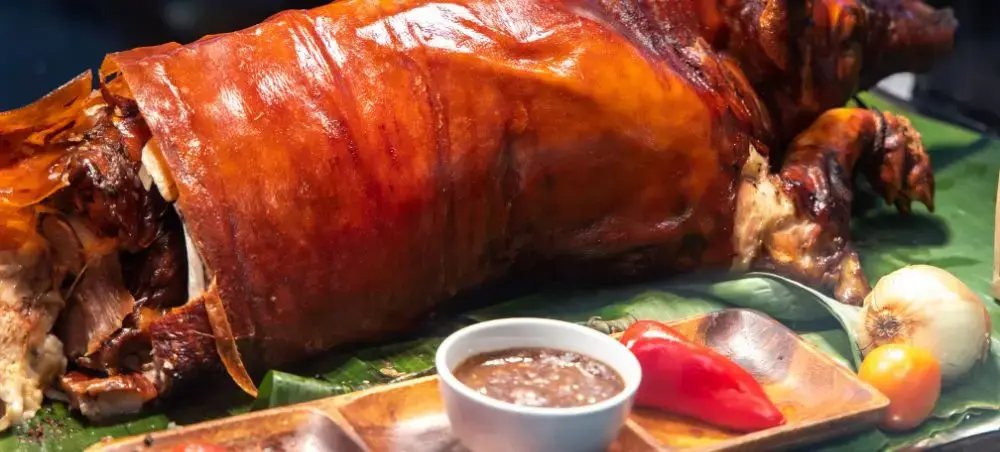 Traditional Filipino lechon roasted pig with crispy golden skin served on banana leaves in Cebu City