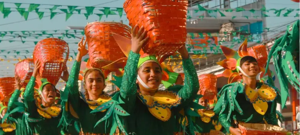 Colorful Sinulog festival dancers in traditional green costumes celebrating Cebu City's vibrant cultural heritage