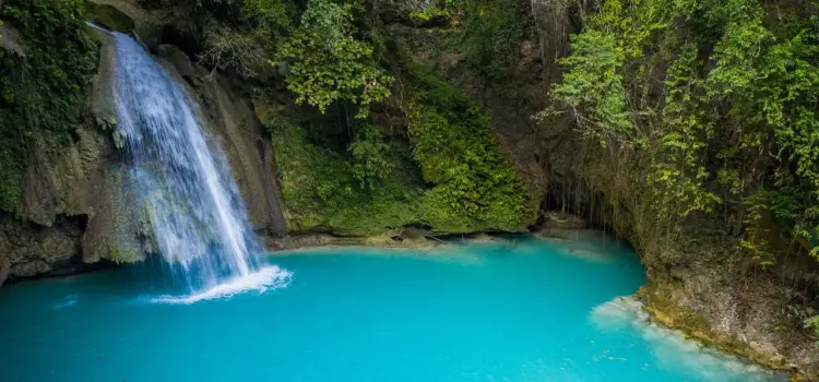 Pristine turquoise waterfall pool surrounded by lush tropical rainforest in Cebu, Philippines