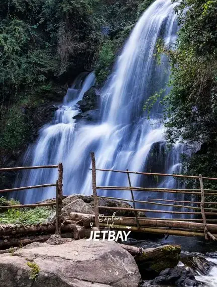 Cascading waterfall surrounded by lush tropical forest in Chiang Mai, Thailand with wooden viewing platform
