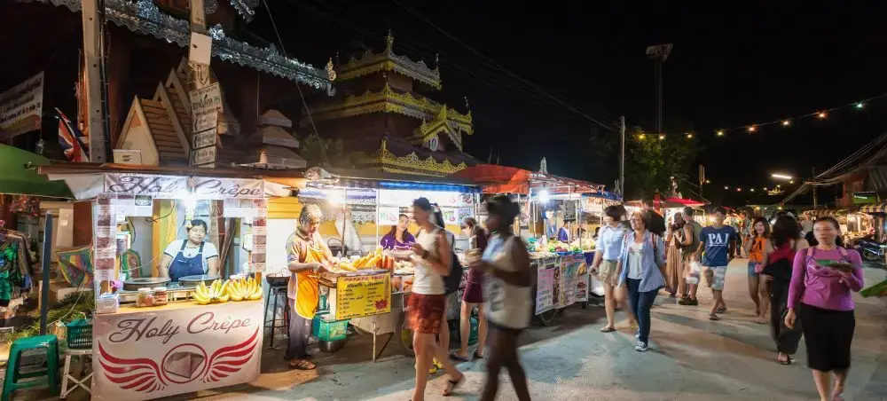 Bustling night market in Chiang Mai with food stalls, local vendors, and tourists exploring authentic Thai cuisine