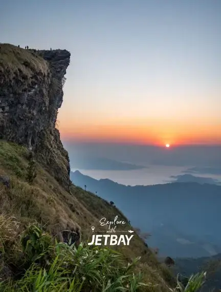 Dramatic sunrise over Chiang Rai mountains with rocky cliff viewpoint showcasing Thailand's scenic highlands