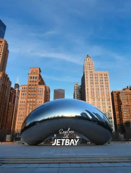 Chicago's iconic Cloud Gate sculpture reflects downtown skyline in Millennium Park under blue sky