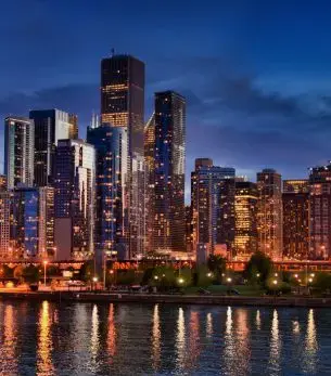 Chicago skyline illuminated at twilight with skyscrapers reflecting in Lake Michigan waters