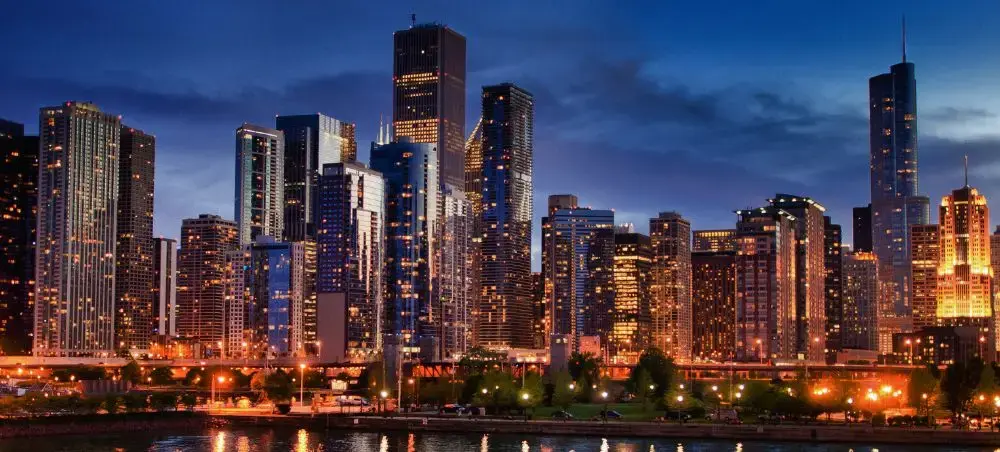 Chicago skyline illuminated at twilight with skyscrapers reflecting in Lake Michigan waters