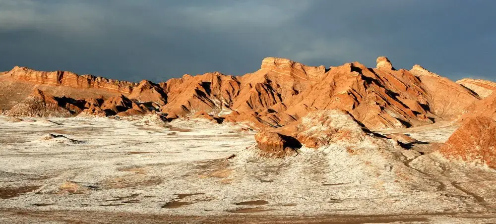 Dramatic red rock formations and salt flats in Chile's Atacama Desert under stormy skies