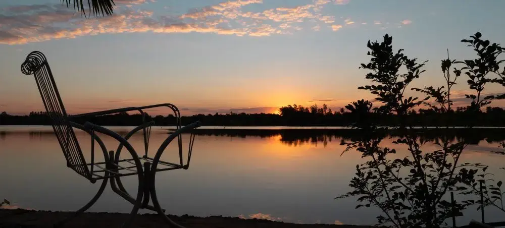 Tranquil lakeside sunset view with silhouetted chair overlooking calm waters near Ciudad Del Este Paraguay